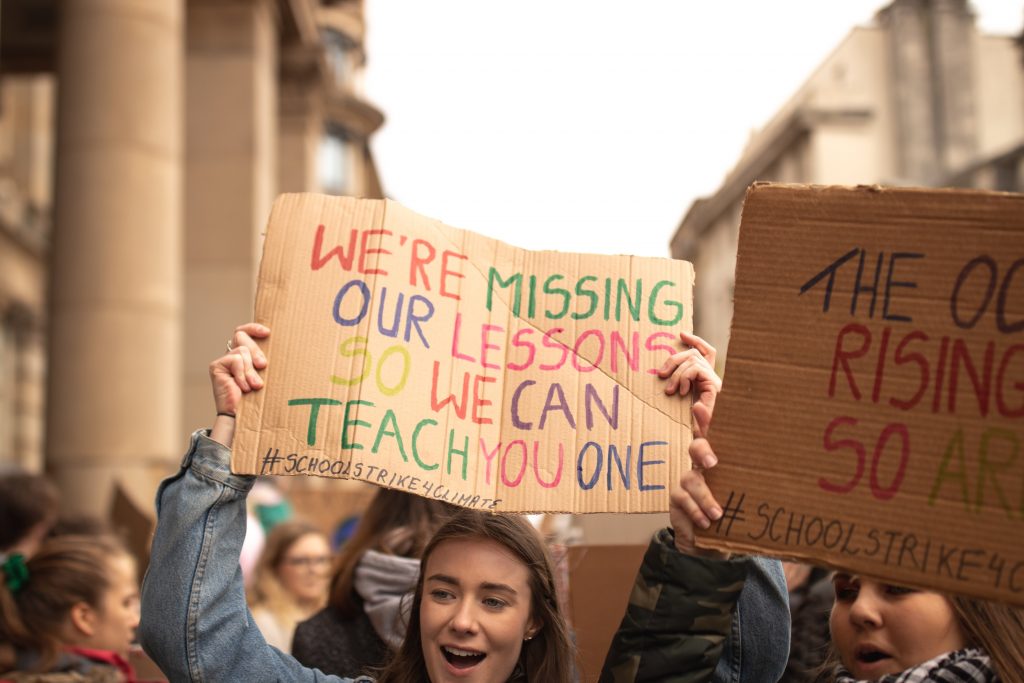 Student at Fridays for Future demonstration holding a sign "We are missing our lessons, so we can teach you one"